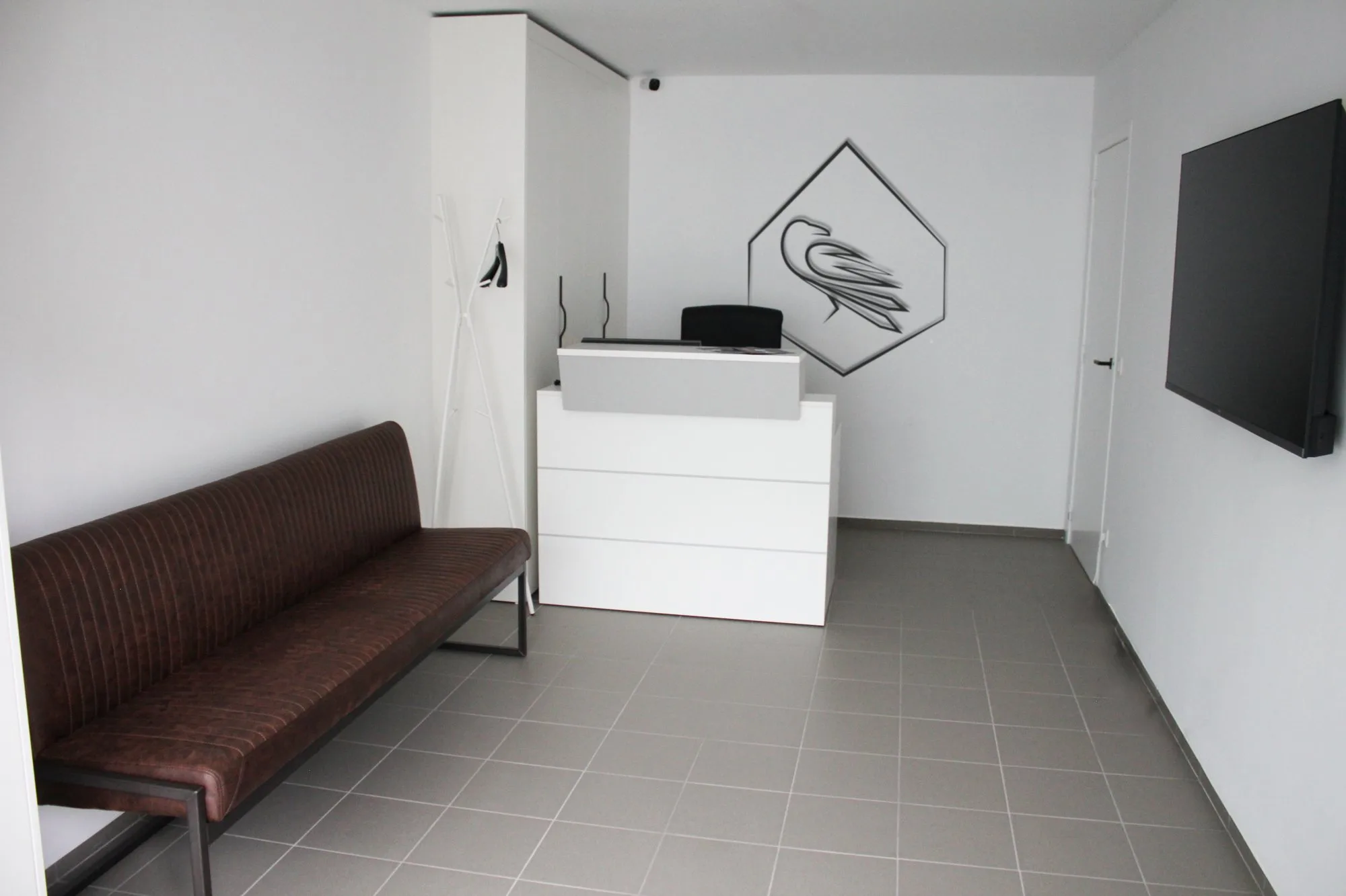 De ontvangstruimte met het logo aan de muur en een leren wachtbank